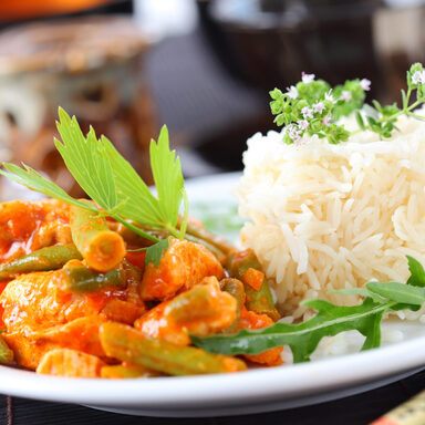 Rote Hühnercurrystreifen mit Reis und Gemüse