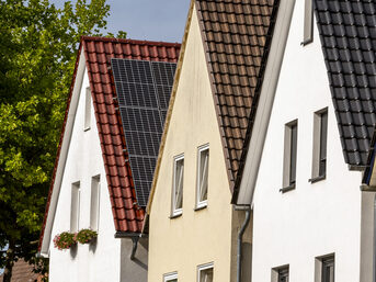 Drei Häuser in einer Reihe, eines hat Solarpaneele auf dem Dach