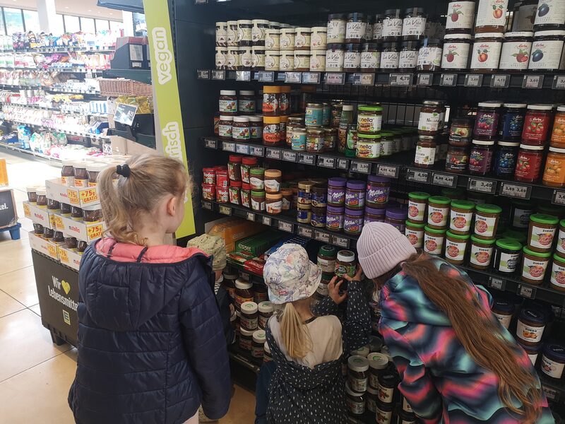 Kinder stehen vor einem Regal in einem Supermarkt