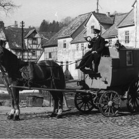 Schwarzweiß Foto von einer Kutsche, die zum letzten Mal Post ausliefert