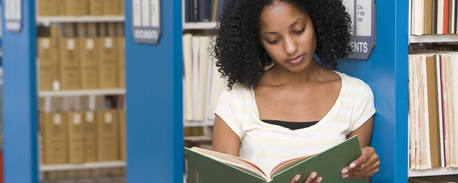 Studentin liest ein Buch in der Bücherei