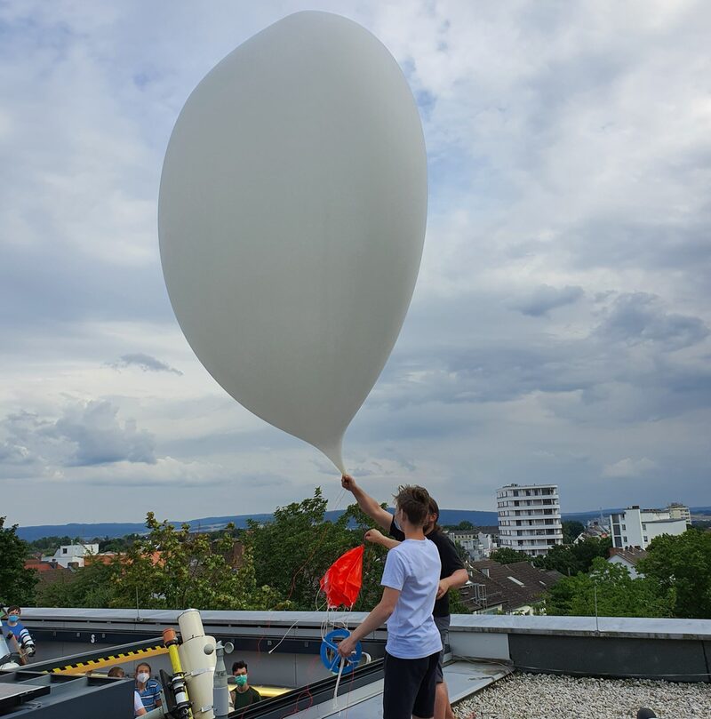 Jugendliche experimentieren draußen mit Gas. Großer Luftballon.