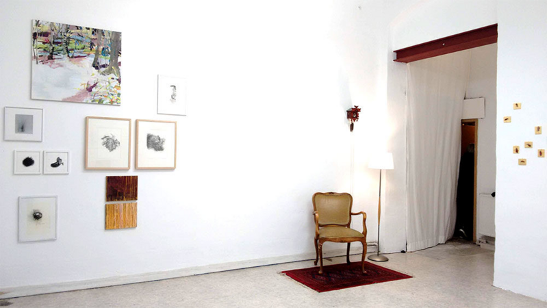 Das Foto zeigt Bilder an der Wand und einen Stuhl. Der steht auf dem Boden.