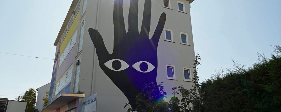 Fassadenbild: Schwarze Hand mit weißen Augen in der Handfläche