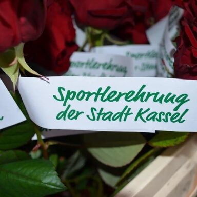 Rosen mit einem Zettel. Text: Sportlerehrung der Stadt Kassel