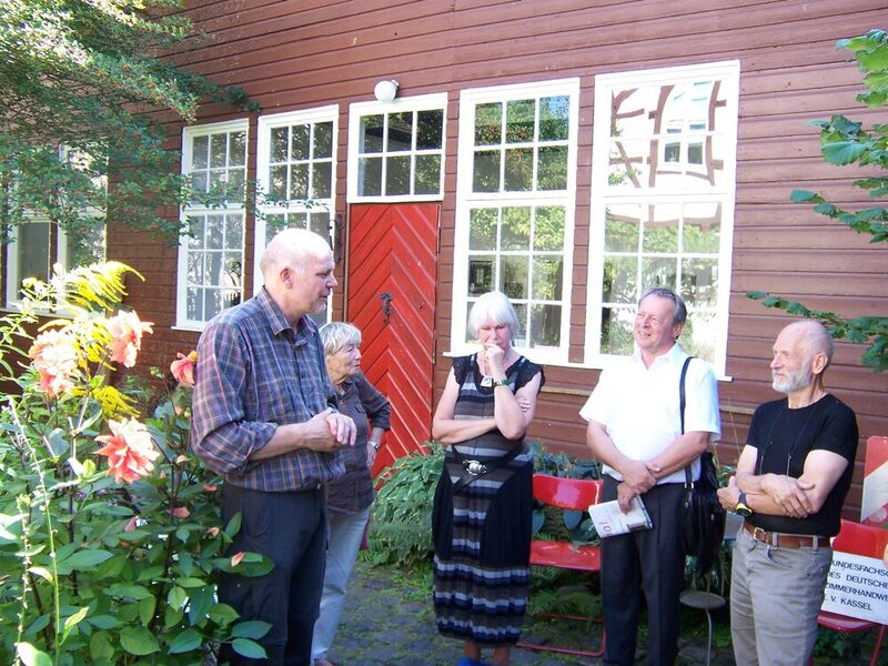 Gruppe vor einem Falun-roten Holzhaus