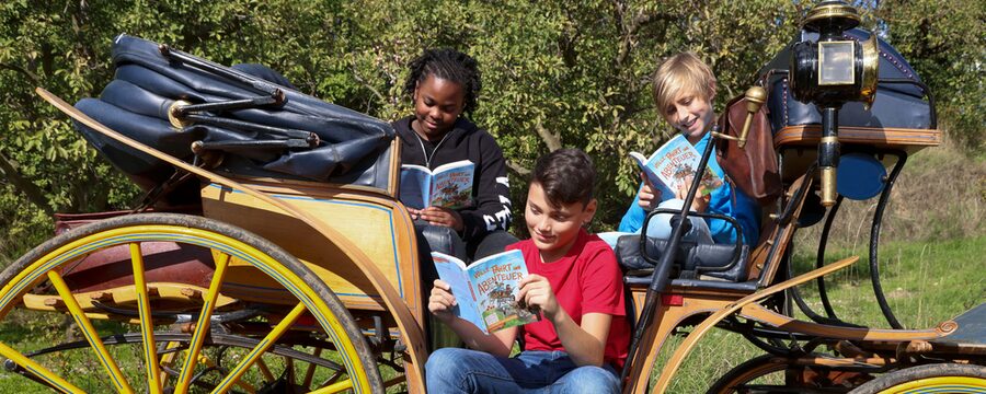 Drei Kinder sitzen in einer Kutsche und lesen