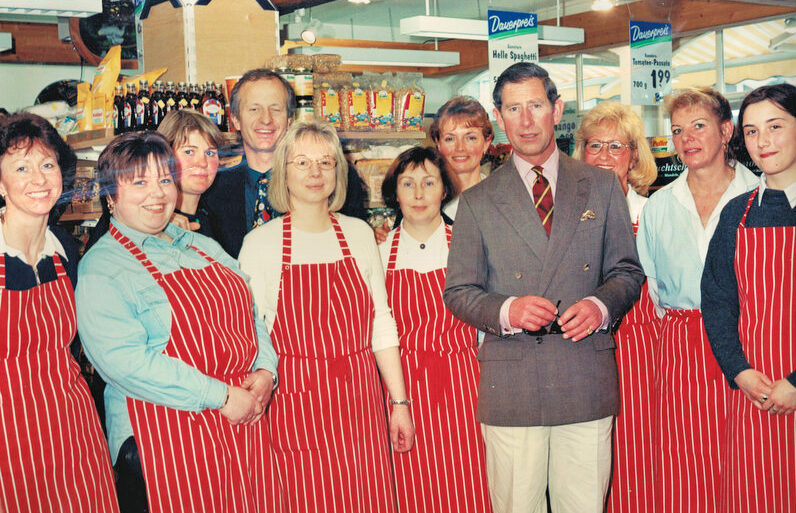 Prinz Charles zusammen mit dem Team des Biomarkts Greger vor Verkaufsregalen