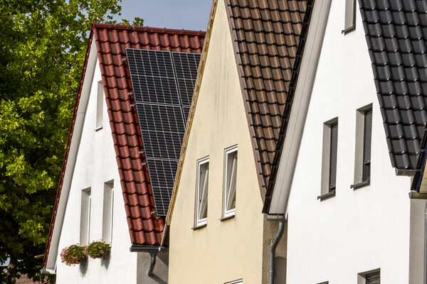 Drei Häuser in einer Reihe, eines hat Solarpaneele auf dem Dach