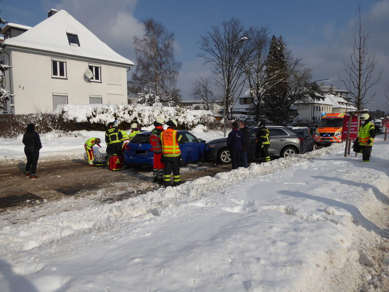 Drei beschädigte PKW stehen an einer verschneiten Straße mit Einsatzkräften