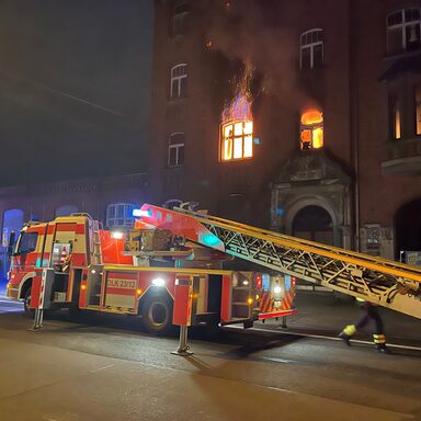 Feuerwehrfahrzeug vor brennendem Gebäude