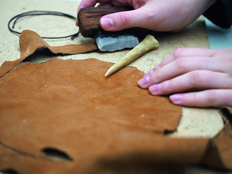 Hände bearbeiten mit Steinzeitwerkzeugen Leder.