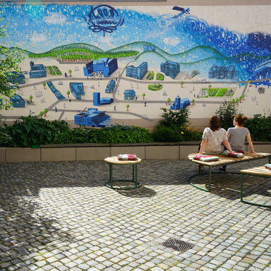 Zwei Frauen sitzen im Innenhof des Stadtmuseums vor einem Graffiti.
