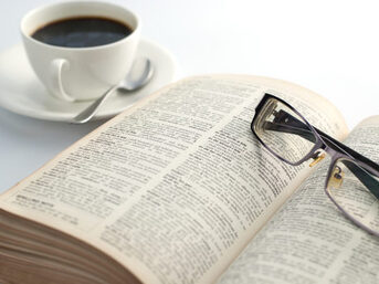 Geöffnetes Buch mit Kaffetasse und Brille