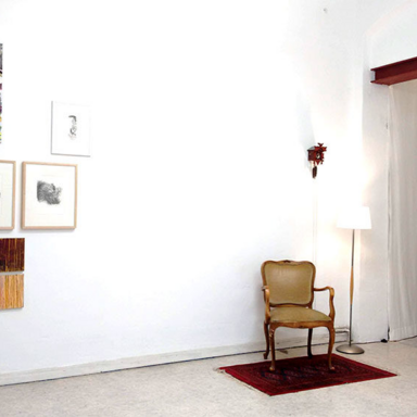 Das Foto zeigt Bilder an der Wand und einen Stuhl. Der steht auf dem Boden.