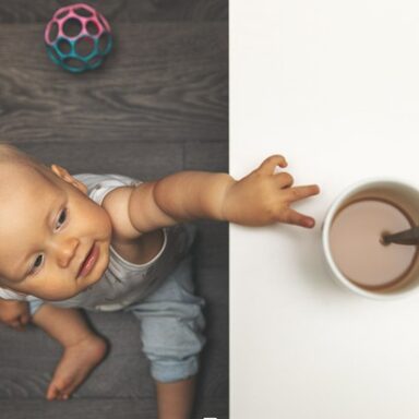 Kleinkind greift nach Kaffeetassse auf dem Tisch