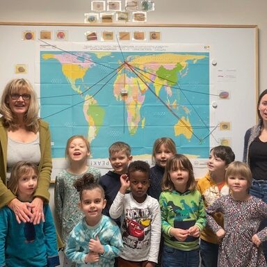 Kinder der Kita Harleshausen II mit ihren Erzieherinnen vor einer Weltkarte.