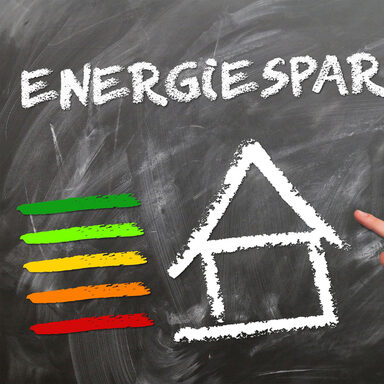 Per Kreide auf einer Schultafel: Das Wort Energiesparen über einem Haus.