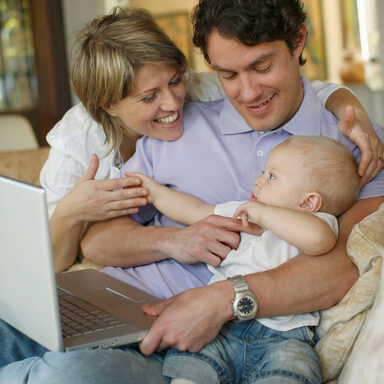 Junge Familie auf Sofa mit Laptop