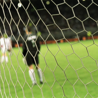 Fußballspieler durch das Netz des Tores fotografiert