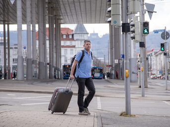Mann mit Koffer vor Bahnhof Kassel Wilhelmshöhe