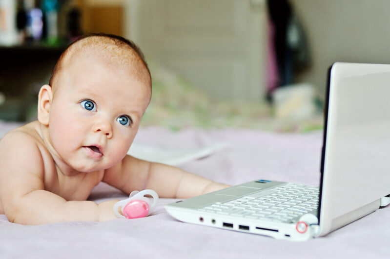Baby liegt vor einem Laptop